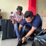 Anggota DPRD Mimika, Darwin Kurnia Rombe membantu salah seorang anak memakai sepatu yang baru diberikan.